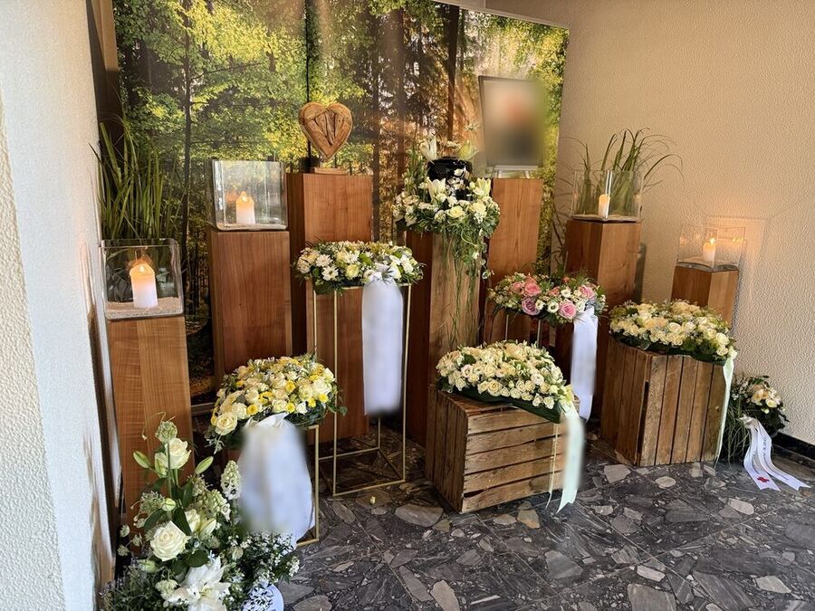 Trauerfeier mit Holzstelen, Kerzen und Blumenschmuck